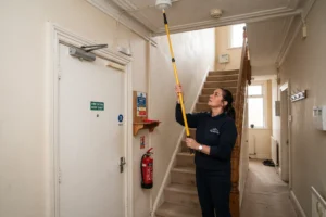 Property manager checking fire alarm system in Manchester HMO property, HMO property management services, landlords in Manchester, HMO landlord responsibilities